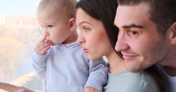 Curioso bambino ragazzo con i genitori guardando fuori attraverso la finestra — Video Stock