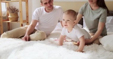 Anne-baba ve bebek yatakta oynuyorlar.