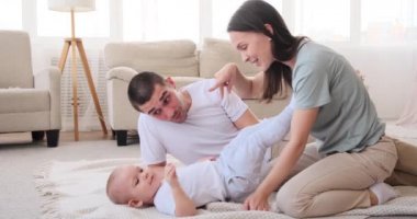 Anne ve babası evde halıda oğluyla oynuyorlar.