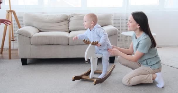 Eltern spielen mit Baby auf schaukelndem Hirsch — Stockvideo