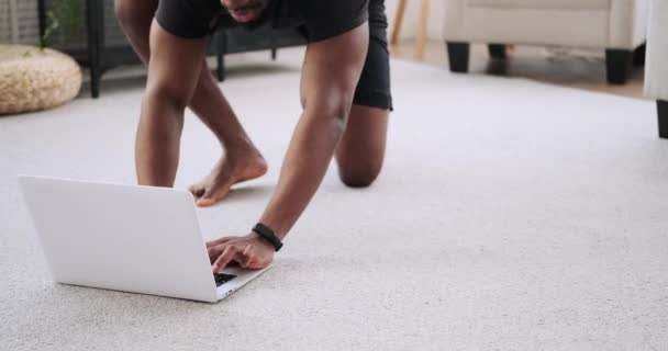 Man met behulp van laptop en het doen van plank oefening thuis — Stockvideo