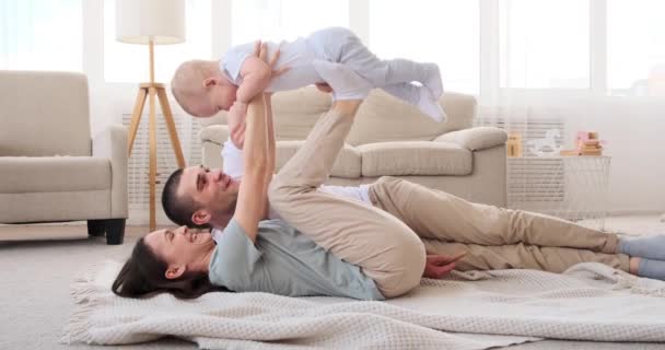 Genitori che giocano con il bambino sdraiato sul tappeto a casa — Video Stock