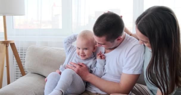 Bebê filho se divertindo com os pais sentados no sofá — Vídeo de Stock