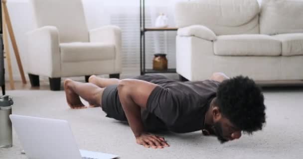 Jovem usando laptop ao fazer push-up exercício — Vídeo de Stock