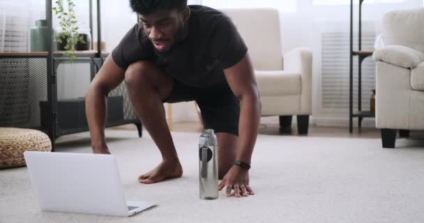 Jongeman met behulp van laptop tijdens push-up oefening — Stockvideo