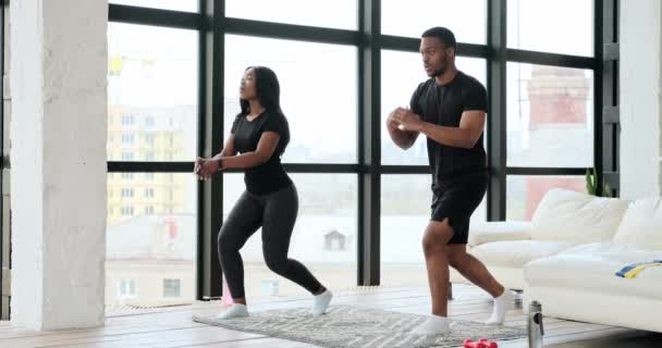 Afro-Amerikaans paar doet lunges in de woonkamer — Stockvideo