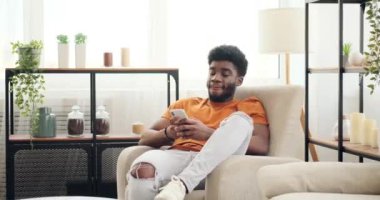 Koltukta dinlenirken cep telefonu kullanan Afrikalı Amerikalı bir adam.