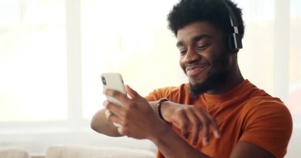 Africano homem americano usando telefone celular enquanto dança e ouvir música em fones de ouvido — Vídeo de Stock