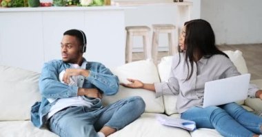 Bilgisayarda çalışan bir kadın dijital tablet kullanarak kocasıyla kulaklıkla eğleniyor.