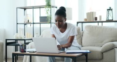 İşkadını dizüstü bilgisayarla çalışıyor ve kanepede oturan belgeleri analiz ediyor.