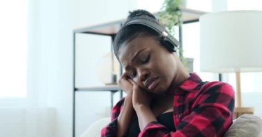 Üzgün kadın kulaklıkla müzik dinliyor.