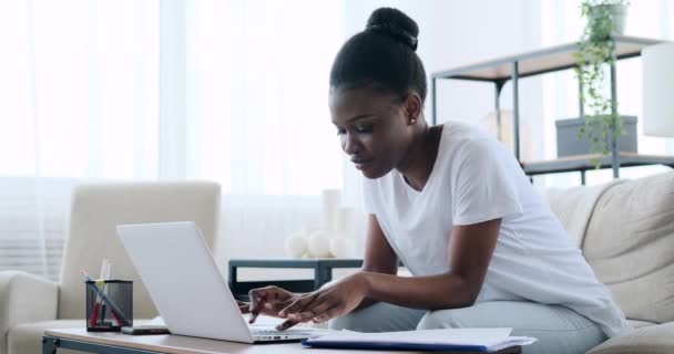 Αφροαμερικανή γυναίκα που χρησιμοποιεί φορητό υπολογιστή στο σπίτι — Αρχείο Βίντεο