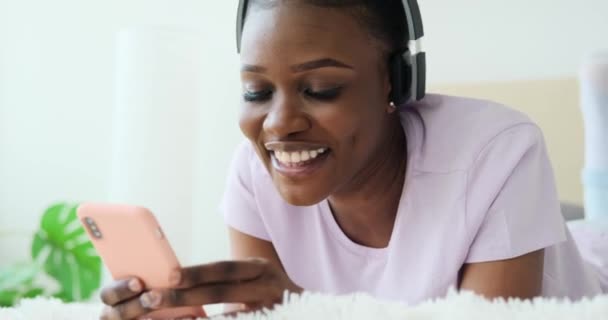 Vrouw zingen lied met behulp van mobiele telefoon en koptelefoon in bed — Stockvideo