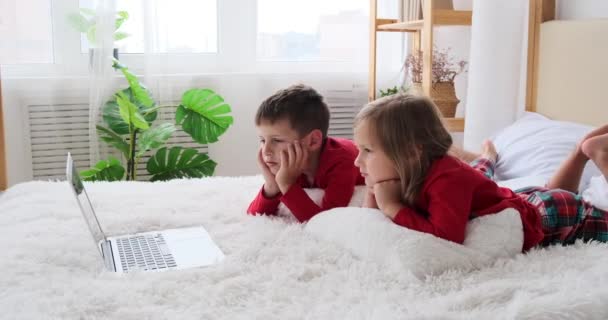 Діти дивляться фільм, що лежить перед ноутбуком — стокове відео