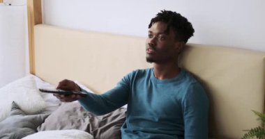 Yatakta televizyon izleyen Afrikalı Amerikalı bir adam.
