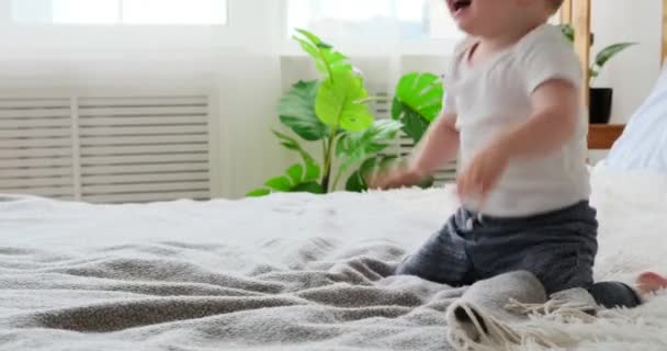 A kisfiú az ágyban játszik. — Stock videók