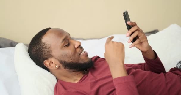 Ευτυχής άνθρωπος που χρησιμοποιεί το κινητό τηλέφωνο στο κρεβάτι — Αρχείο Βίντεο