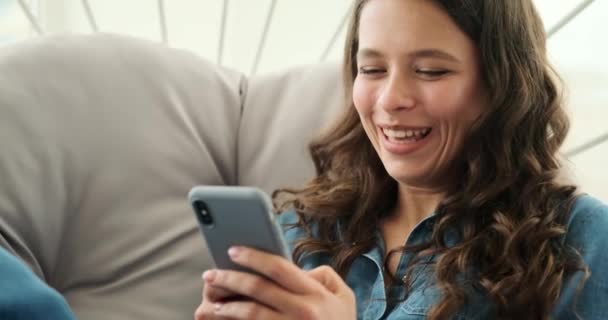 Kvinner ler når de bruker mobiltelefon sittende på luksusstol – stockvideo