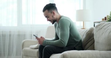 Yakışıklı adam koltukta cep telefonu kullanarak mesaj atıyor.