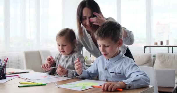 Matka pomáhá dětem kreslit na papír — Stock video