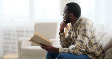 Koltukta kitap okuyan düşünceli bir adam.