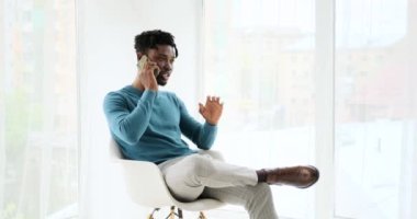 Genç Afrikalı Amerikalı adam cep telefonuyla konuşuyor.