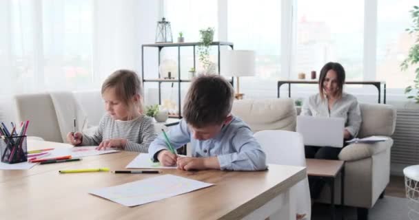 Kinder malen auf Papier, während die Mutter zu Hause am Laptop arbeitet — Stockvideo