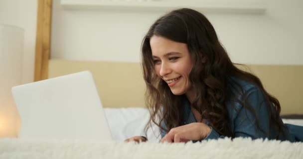 Gelukkig vrouw met behulp van laptop liggend in bed — Stockvideo