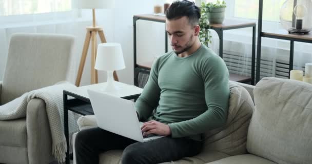 Man använder laptop sitter på soffan hemma — Stockvideo