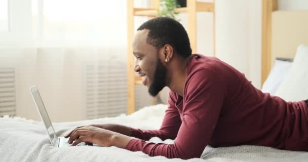 Mann tippt auf Laptop im Bett — Stockvideo