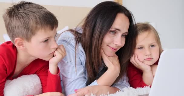 Mutter mit Kindern schaut Film auf Laptop im Schlafzimmer — Stockvideo