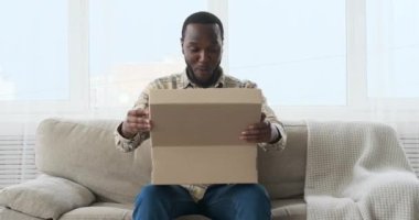 Koltukta oturan heyecanlı adam yeni ayakkabılarını çıkarıyor.