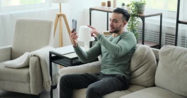 Genç adam cep telefonuyla görüntülü konuşma yapıyor.