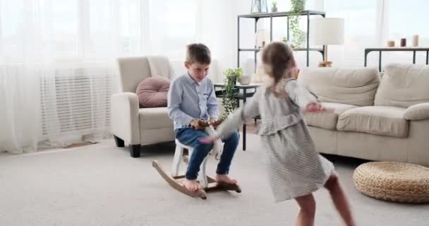 Хлопчик насолоджується іграшкою оленя з сестрою біжить навколо — стокове відео