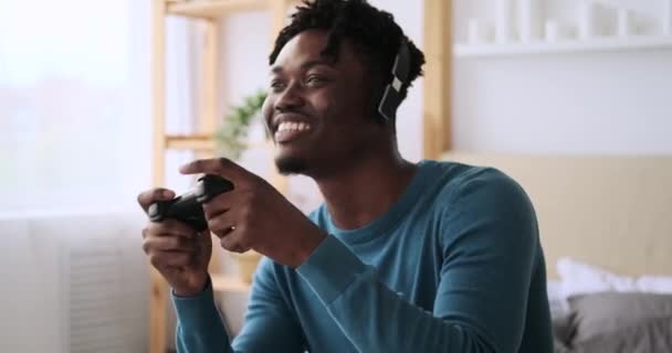 興奮した男でヘッドフォン再生ビデオゲームオンベッド — ストック動画