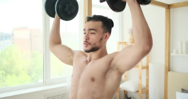 Молодий чоловік робить плечовий прес з гантелями — стокове відео
