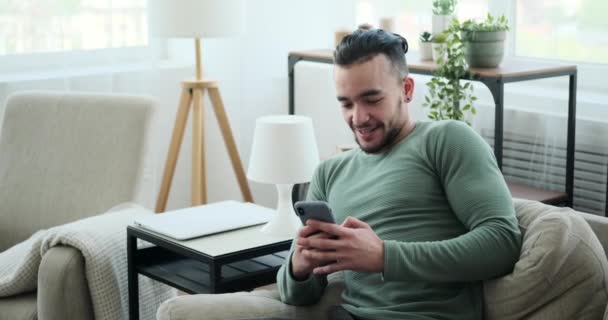 Hombre joven usando el teléfono móvil en el sofá — Vídeo de stock