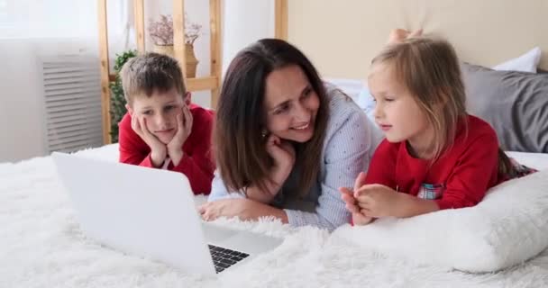 Madre con bambini che usano il computer portatile sul letto — Video Stock