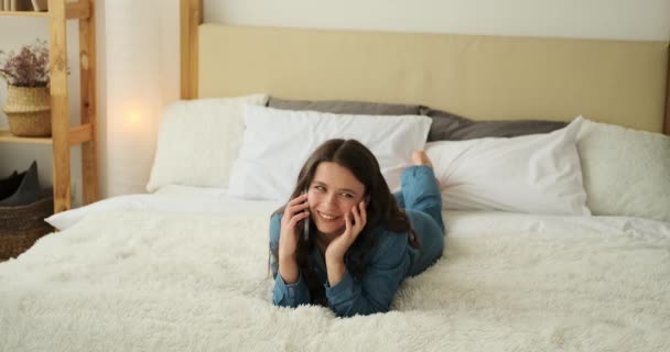 Jonge vrouw praten op mobiele telefoon liggend op bed — Stockvideo