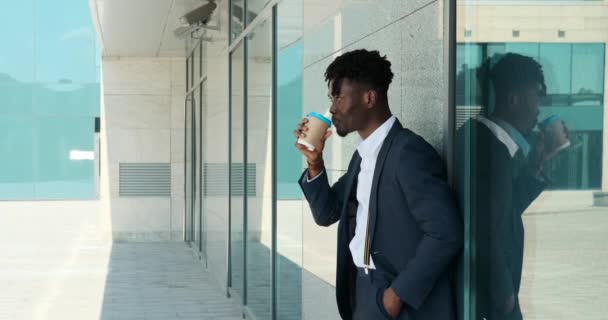 Zakenman drinken koffie leunend op de muur van moderne kantoorgebouw — Stockvideo