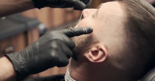 Fryzjer wykonuje zabieg gwintowania na twarzy — Wideo stockowe