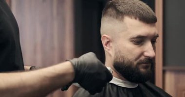 Berber eller traş makinesiyle saç kesiyor.