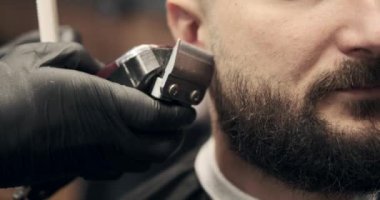 Berber elleri tıraş makinesi kullanarak sakal tıraşı oluyor.