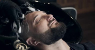 Berber müşterinin kafasını şampuanla yıkıyor.