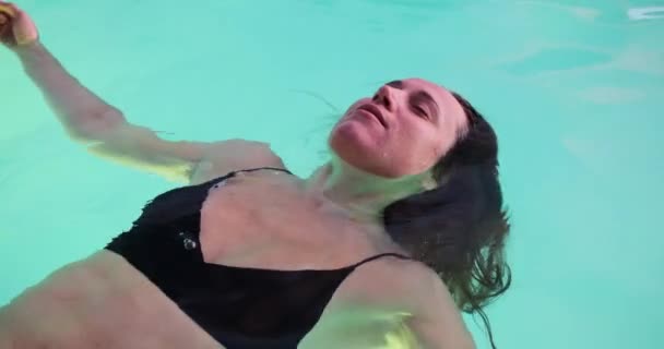 Giovane donna galleggiante sulla superficie della piscina — Video Stock
