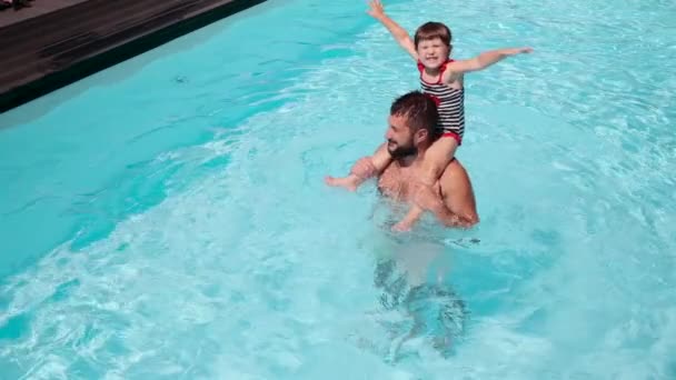 Otec nosí dceru na ramenou v bazénu — Stock video