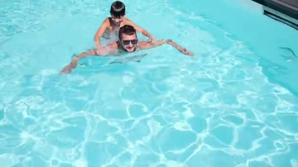 Ung mand med søn svømmer på ryggen over vandet – Stock-video