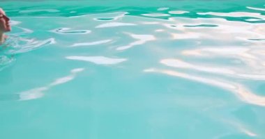 Havuzda yüzerken gülümseyen genç kadın