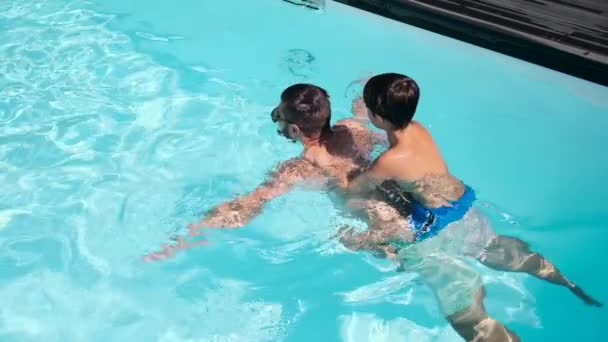 Père avec son fils sur le dos nageant dans la piscine — Video