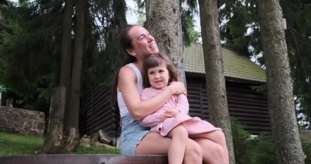 Nő beszél a lányával ül a fa padon — Stock videók